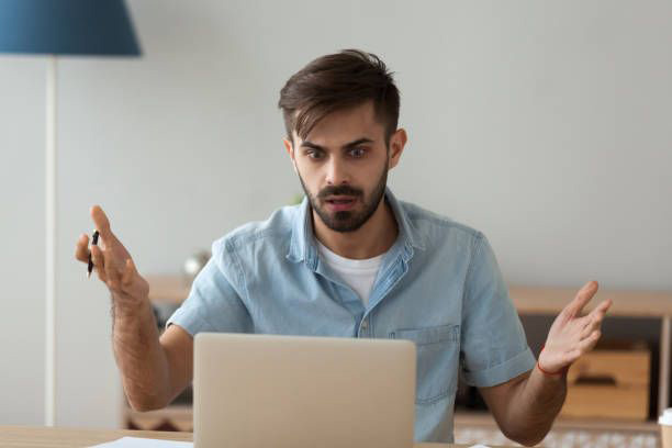 Man looking at laptop in confusion